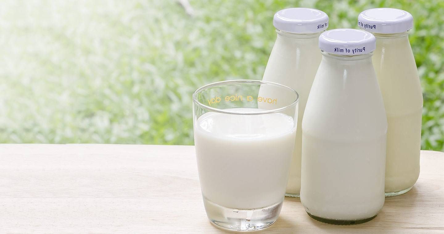 Bottiglie e bicchiere di latte fresco su tavolo in legno